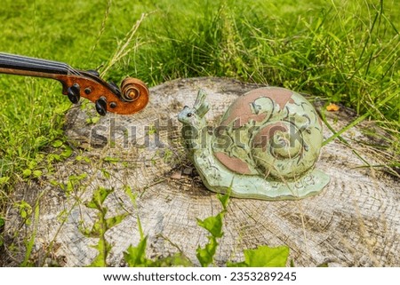 A photography of a violin snail and a decorative snail in a garden symbolizing 2 snails meeting each other.