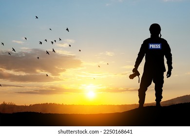 Photojournalist silhouette documenting war or conflict. Photojournalist at sunset. War, army, technology and journalist work concept.