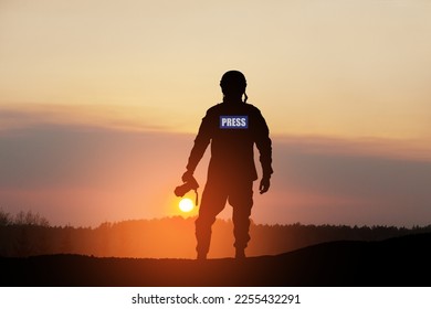 Photojournalist silhouette documenting war or conflict. Photojournalist at sunset. War, army, technology and journalist work concept.
