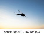 Photos of Military Helicopter flying against sunset.Flying a helicopter in the blue sunny sky