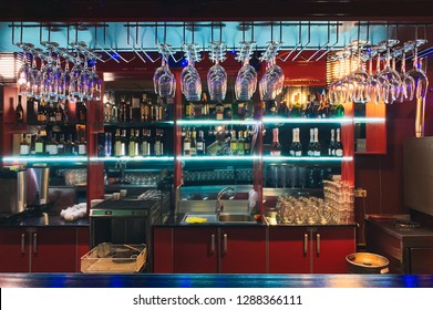 Photos of a stylish bar with colorful bright interior in the restaurant. Alcohol bars, bar counter, bartender's workplace. Empty the top of the wooden table with counter bar and bottles background