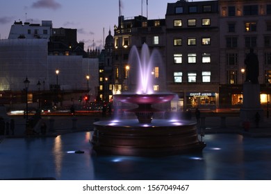 Photos taken November 18th 2019 at trafalgar square London. Image shows water fountain, long eposure trafiic, retail units in the background and cafes. 
