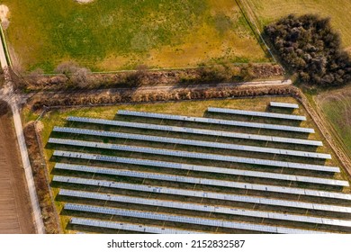 Photovoltaic Modules Of A Solar Farm Bordering A Dirt Road And Agricultural Fields From A Drone's Point Of View