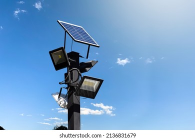 Photovoltaic Panel Systems And Hd Floodlights On Black Metal Pole In Public Park, Soft And Selective Focus.