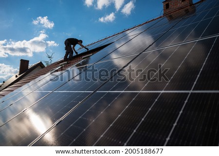 Photovoltaic panels on the roof and intaller in the background