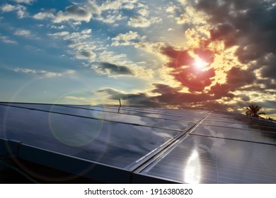 Photovoltaic Panels On The Roof's Building With Sunrise And Cloudy Blue Sky Background, Concept For Using Natural Energy To Reduce Global Warming And Expenses From The Use Of Electricity In The House.