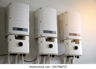 Photovoltaic power converter system unit installed on wall. Electrical converter converts  direct current (DC) output of a photovoltaic (PV) solar panel into alternating current (AC). Clean technology - Shutterstock ID 2057988737