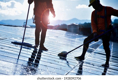 Photovoltaic Technicians Are Using Mop And Water To Wash And Clean The Surface Of The Solar Cell Panels Which Are Dirty With Dust And Birds'droppings In The Afternoon. Soft And Selective Focus.