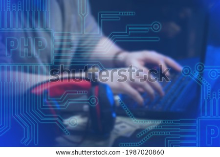 PHP logo. Programmer near computer. Man works next to a laptop. Website development using PHP. Hands on keyboard. Website development. Programmer writes PHP code for website. Hypertext Preprocessor 