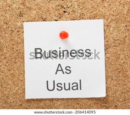 The phrase Business as Usual typed on a piece of note paper and pinned to a cork notice board
