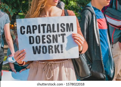 The phrase " Capitalism doesn't work! " drawn on a paper in woman hands. Caucasian woman with light hair holds a cardboard with an inscription. Government. Politics. Power. Economics. Economy