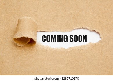 The phrase Coming Soon appearing behind ripped brown paper. Concept about upcoming promising event approaching in near future.
