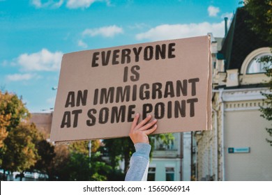 The phrase " Everyone is an immigrant at some point " on a carton banner in men's hand. Human holds a cardboard with an inscription. Government. Power. Immigration. Expats - Shutterstock ID 1565066914