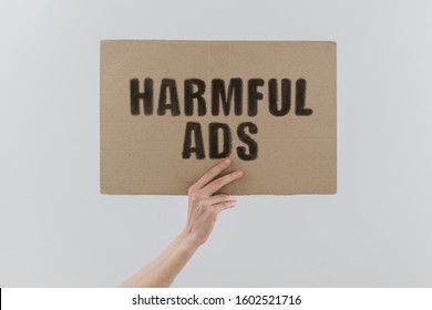 The phrase " Harmful ads " on a banner in men's hand. Human holds a cardboard with an inscription. Internet. Media. Advertising. Harassment. Humiliate. Depressive - Shutterstock ID 1602521716