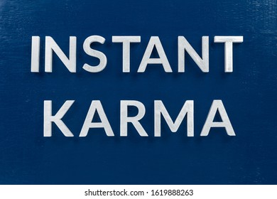 The Phrase Instant Karma Laid With Silver Metal Letters On Classic Blue Painted Board Background