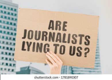 The phrase " Are journalists lying to us? " on a banner in men's hand with blurred background. Truth. News media. Information. Disinformation. Profession. Liar. True