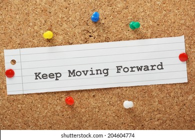 The phrase Keep Moving Forward typed on a piece of paper and pinned to a cork notice board