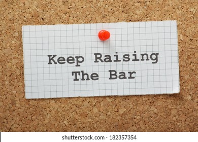 The Phrase Keep Raising The Bar On A Piece Of Graph Paper Pinned To A Cork Notice Board. A Concept For Raising Standards And Setting Targets As A Form Of Motivation.