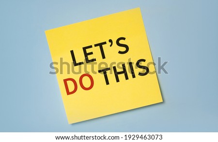 The phrase Let's Do This in red and black text on a yellow sticky note posted on a blue board