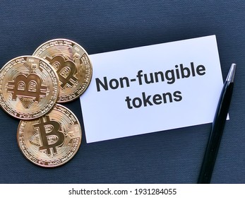 Phrase NON FUNGIBLE TOKENS written on white card with bitcoins isolated on black background. Cryptocurrency and finance concept.