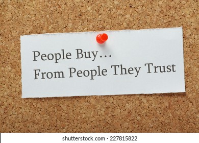 The phrase People Buy From People They Trust on a cork notice board as a concept for businesses to build customer trust and loyalty to their product or service.