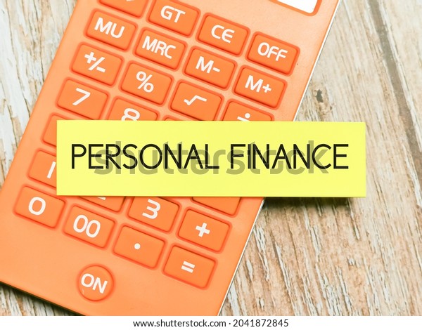 Phrase PERSONAL FINANCE written on\
sticky note with calculator. Business and finance\
concept.