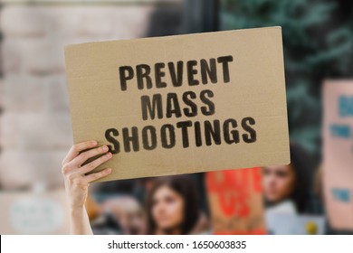 The phrase " Prevent mass shootings " on a banner in men's hand. Human holds a cardboard with an inscription. Attack. Terrorism. Terror. Criminal. Killings. Safety. Protect us. Killer