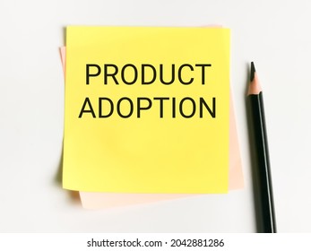 Phrase product adoption written on sticky note with a pencil.