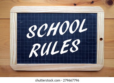 The Phrase School Rules In White Text On A Slate Blackboard Placed On A Wooden Surface