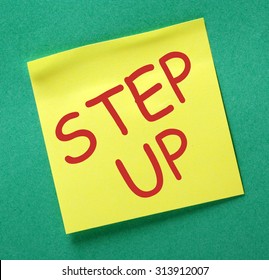 The Phrase Step Up In Red Text On A Yellow Sticky Note Posted On A Green Notice Board As A Reminder To Make A Contribution