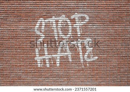 The phrase Stop Hate spray painted in white on a brick wall. Concept of peace, understanding and unity.