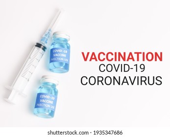 Phrase VACCINATION COVID 19 CORONAVIRUS Written On White Background With Two Bottles Vaccine And Syringe.