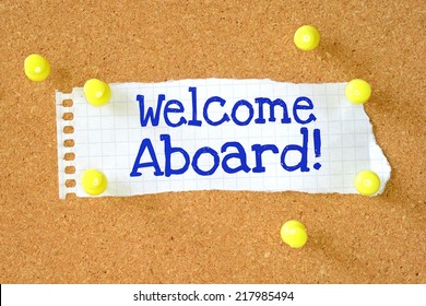 The Phrase Welcome Aboard! Typed Onto A Scrap Of Lined Paper And Pinned To A Cork Notice Board. A Phrase Used To Welcome A New Employee Or Team Member.