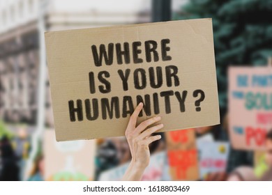 The phrase " Where is your humanity? " on a banner in men's hand. Human holds a cardboard with an inscription. Nature. World. Justice. Peace. Globe. Animal rights. Fight. Escalation. Harm to ecosystem - Powered by Shutterstock