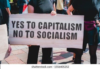The phrase " Yes to capitalism, no to socialism " drawn on a carton banner in hand. A girl holds a cardboard with an inscription. Girls on the street. Protest. Power. Government
