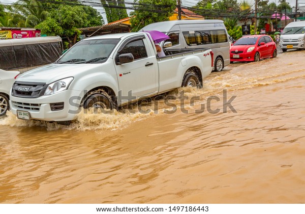 Phuket, Thailand - Aug 2015: Thailand flood.\
Flooded streets and roads in Phuket island after passing a tropical\
cyclone with storm, typhoon and hurricane. Cars and motorcycles\
ride on wheels in water