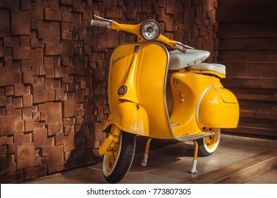 Phuket, Thailand - December 12, 2017: 1964 vintage yellow Vespa parking at the wooden wall of the restaurant. The iconic Italian designed scooter.