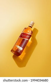 Phuket, Thailand- Jan 2021. Johnnie Walker Red Label blended whisky isolated on color  background. Johnnie Walker is the most widely distributed brand of blended Scotch whisky in the world.