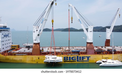 Phuket,Thailand, 20,March,2021: Sailing Catamaran Hanging On The Crane Slings Of An International Cargo Ship, Sailing Catamaran Dream Yacht Charter In The Process Of Loading For Shipment To The Owner