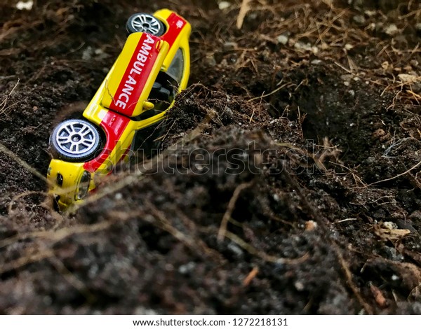 Phuket,Thailand-Jan 1,2019:Model toy car yellow\
rollover accident.Car flipped on mountain.Driving speed and \
Traffic signs\
concept.