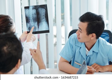 Physiatrists and orthopedic surgeon discussing neck and spine x-rays of patient - Powered by Shutterstock