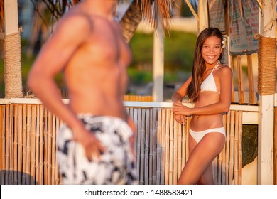 Physical Attraction Asian Woman Flirting With Man At Beach Pool Bar Seducing Looking At His Fit Body With Abs. Sexy Handsome Model Summer Flirt.