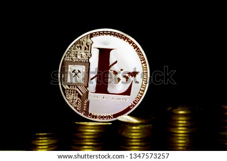 Physical Litecoin LTC coin on a dark background and gold coins.