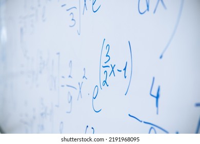 Physical And Mathematical Formulas Written With A Blue Marker On A White Board In A High School Classroom. Abstract Background Close-up