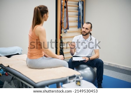 Physical therapist and athletic woman discussing about treatment plans at health club.