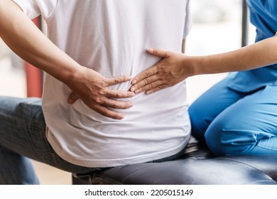 Physical therapist is examining the injured arm, waist and neck muscles of an athletic male patient. - Shutterstock ID 2205015149