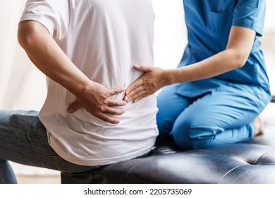 Physical therapist is examining the injured arm, waist and neck muscles of an athletic male patient. - Shutterstock ID 2205735069