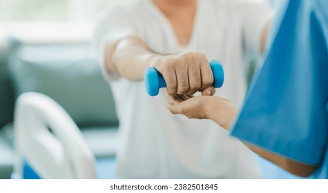 Physical therapist giving exercise by maintaining dumbbells on the arms and shoulders of a male patient. Physical therapy concept - Powered by Shutterstock