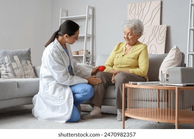 Physical therapist massaging senior woman's knee with ball at home - Powered by Shutterstock