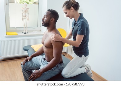 Physical Therapist Massaging A Young Black Man On Shoulder After A Sport Injury